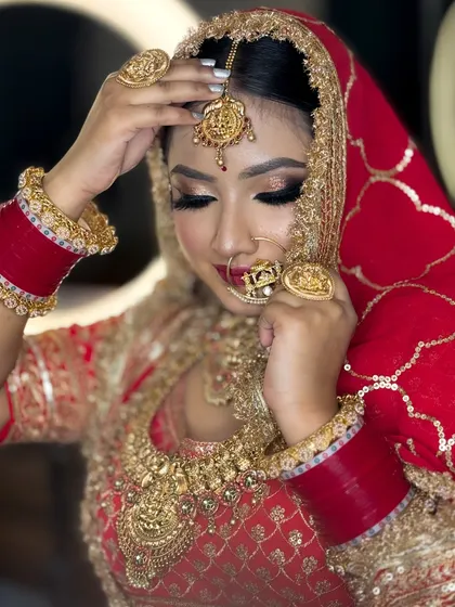 A close-up shot focusing on the bride's beautiful eye makeup and the intricate design of her nose ring and maang tikka.