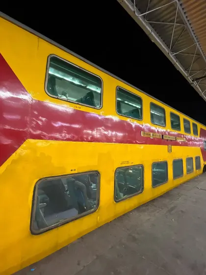 The distinctive red and yellow exterior of the double-decker express train at a station platform at night.