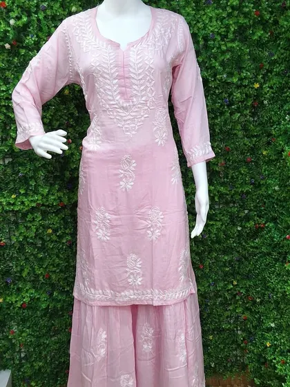 A soft pink Lucknowi Chikankari kurti paired with a matching sharara. The delicate white embroidery gives it a very feminine and graceful look, perfect for daytime events.