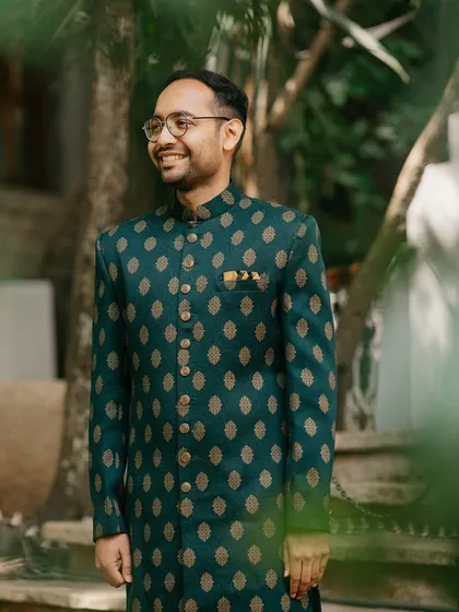 The groom looking dapper in a dark green sherwani, ready for the Mehendi festivities.
