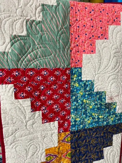 A detail shot of a Log Cabin quilt, showing the feather-like quilting in the white spaces.