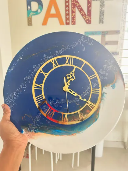 A custom resin clock with a deep blue face and gold Roman numerals, featuring abstract swirls.