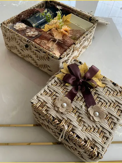 A different angle of the beige jute hamper, showing the rich brown ribbon and pearl-centered flowers that add a touch of elegance.