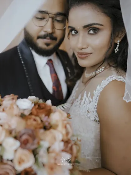 An intimate portrait of the couple, the bride looking directly at the camera from under her veil, creating a captivating and romantic image.