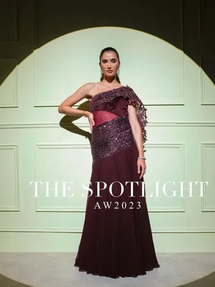 A full campaign shot of the one-shoulder wine-colored gown, a perfect example of modern, structured elegance.