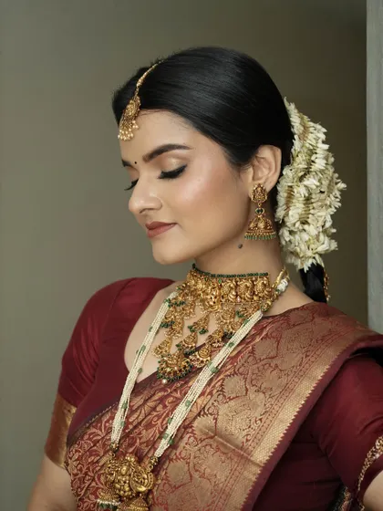 A side profile highlighting the soft, shimmering eye makeup and the elegant hairstyle. The skin is absolutely flawless.