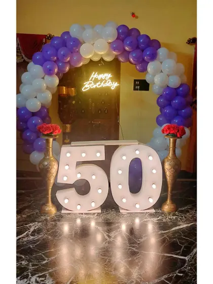 A family celebrating a 50th birthday with our marquee number setup. The large, lit-up "50" provides the perfect centerpiece, framed by a purple and white balloon arch for a festive and memorable family photo.