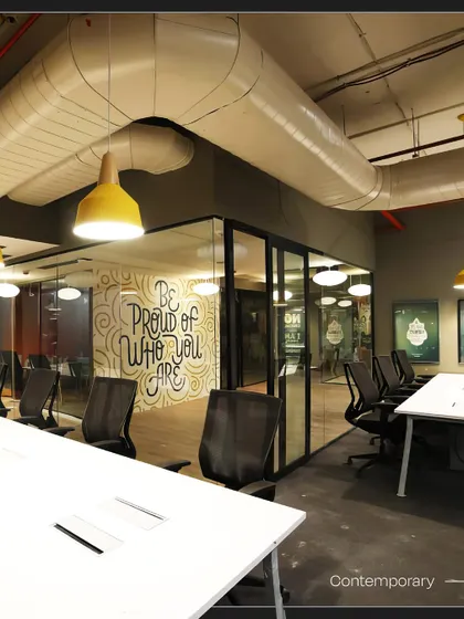 An open workspace at Innov8 with another motivational mural, 'Be Proud Of Who You Are'. The design combines industrial elements like exposed pipes with contemporary office furniture.