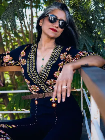 This shot highlights the intricate embroidery on the jumpsuit.