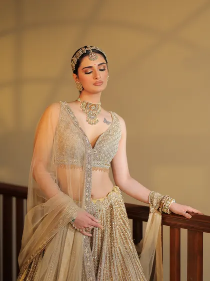 This shot captures the bride in a moment of quiet contemplation, with the light beautifully hitting her golden outfit.