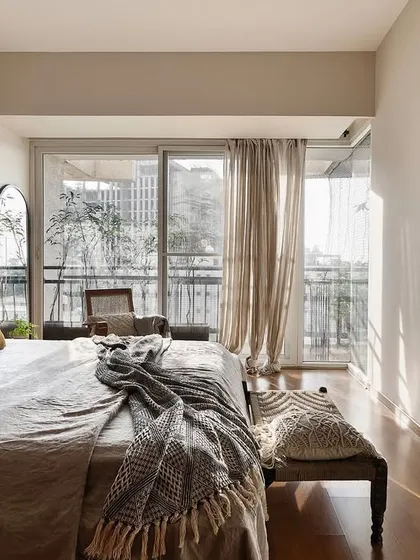 Sunlight streams into the 'Reweave Stories' bedroom, highlighting the calm and airy feel of the space. The design prioritizes natural light to make the apartment feel bright and spacious.