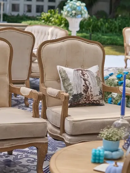 Elegant, French-style armchairs with custom-printed cushions, arranged on the blue and white tiled floor.