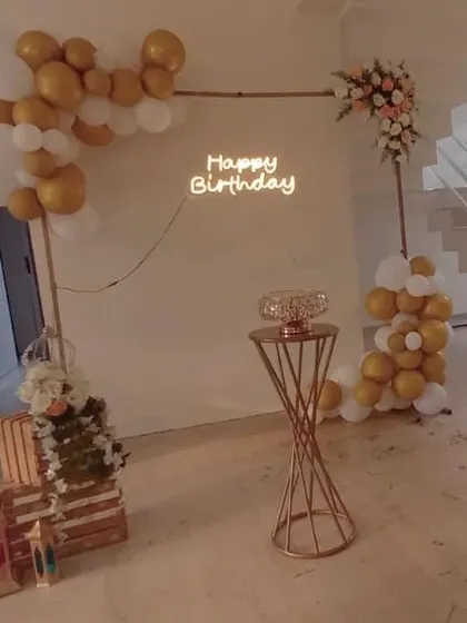 A simple and modern decor for a 30th birthday. We used a minimalist frame with white and gold balloons and a "Happy Birthday" neon sign for a chic and understated celebration.