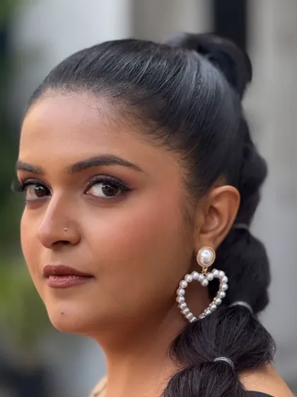 For this look, we focused on clean lines and statement accessories. The bubble ponytail and heart-shaped pearl earrings add a touch of personality to the classic black and white dress.