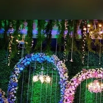 The full view of the enchanted forest theme, showing how the multiple floral arches, hanging chandeliers, and lush green backdrop come together. This immersive design makes the main stage feel like a fairytale setting.