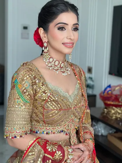 A bride ready for her wedding day in a stunning Rimple and Harpreet ensemble. Her hair is in a braided updo with a single red rose, adding a touch of romance.