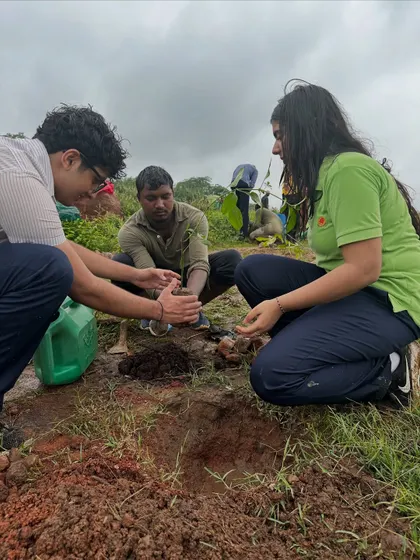 A student from The Shri Ram School gets guidance from our team member on how to properly plant a sapling during their drive at Aravali Nagar Van.