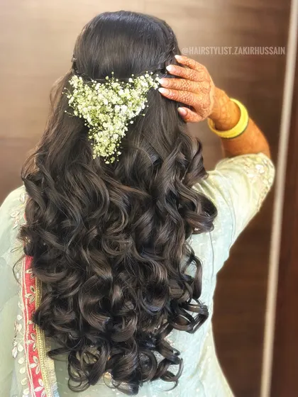 For this Mehendi look, I styled the hair in a half-updo with a braided crown and voluminous curls. I then created a heart shape using fresh baby's breath for a unique and romantic touch.