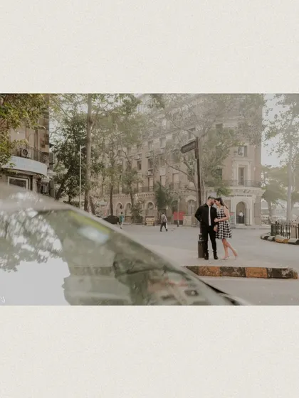 A unique perspective shot, using a car's reflection to frame the couple against the city's architecture.