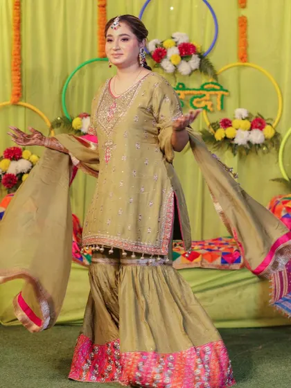 The bride in a joyful, welcoming pose at her Mehndi ceremony.