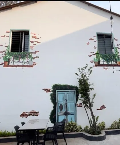 A wider view of the cafe mural, showing how the artwork transforms a large, plain white wall into a picturesque scene.