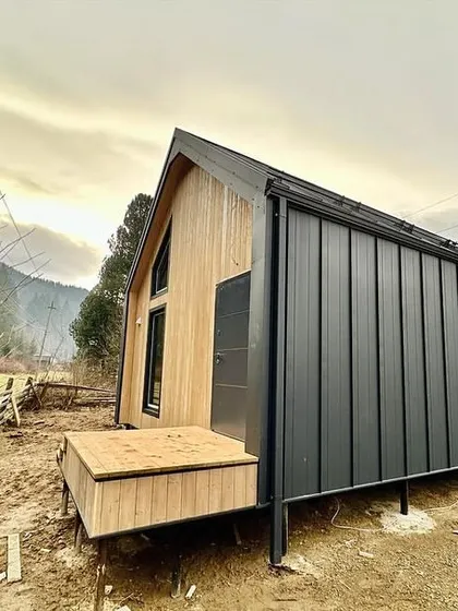 A modern barn-style prefabricated home under construction in a mountain setting. This design combines traditional aesthetics with the speed and efficiency of modular building techniques.