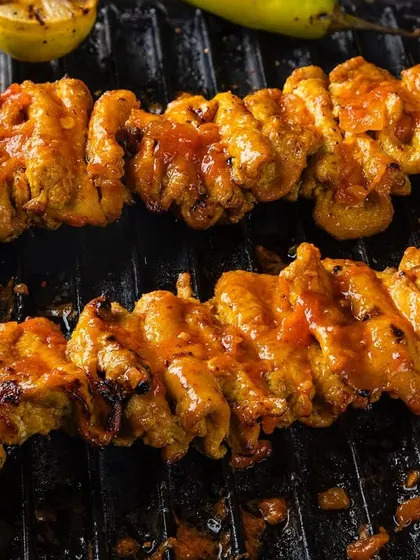 Chicken tikka skewers on a grill, showing the moment of cooking. This dynamic shot for Punjab Grill is designed to evoke the sounds and smells of a barbecue.