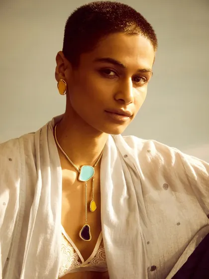A layered necklace look against a simple white top. This demonstrates how the jewelry can be styled in a more casual, contemporary way.