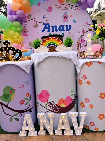 A close-up of the pedestals from Anav's party, decorated with bird illustrations and topped with a crown and light-up rainbow.