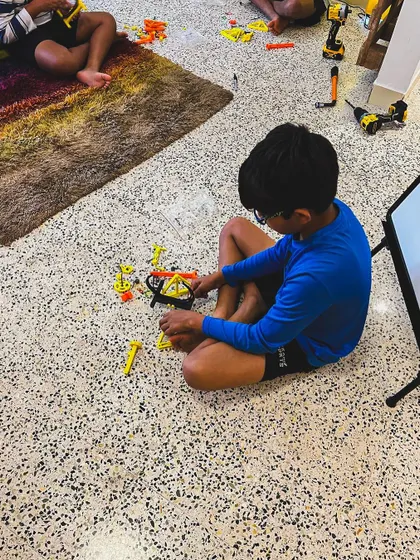 Our workshops are designed for active participation. Here, a student is fully engaged in assembling a project on the floor, showing the focus and dedication that hands-on tasks inspire.