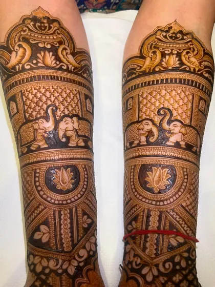 This full leg design features bands of royal elephants and is topped with a 'jharokha' holding two peacocks, creating a symmetrical and regal look.