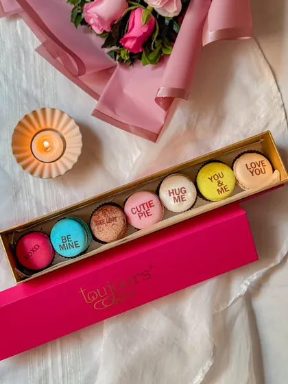 A bright pink box of my Valentine's Day message macarons, with sweet phrases like "Be Mine," "Cutie Pie," and "You & Me." These are a playful and colorful way to express your feelings.
