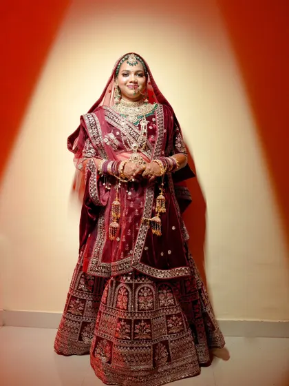 A striking bridal portrait using dramatic spotlighting against a red background. The bride's pose and the lighting create a regal and powerful image.