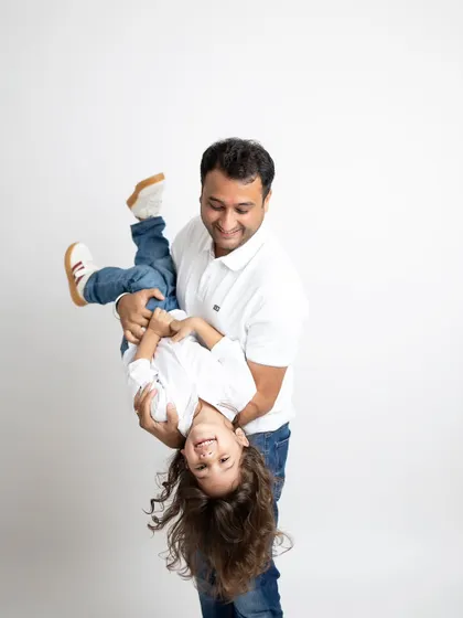 It's the playful, unscripted moments that often make the best memories. I love capturing the fun side of family, like this shot of a father playfully holding his child upside down during our studio session.