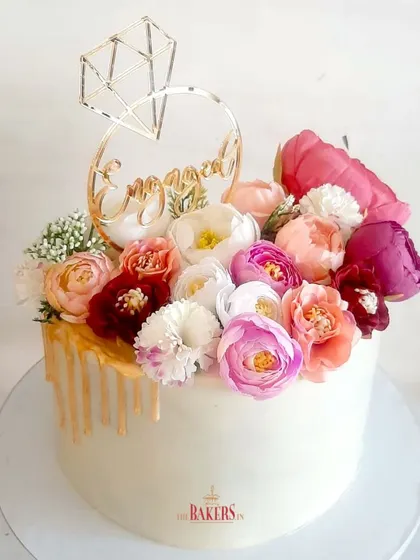 What better way to celebrate an engagement than with this stunning floral drip cake? This no-fondant cake features a cascade of fresh, colorful flowers over a smooth white chocolate ganache with an elegant gold drip.