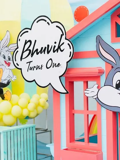 A welcome sign for "Bhuvik Turns One," featuring Bugs Bunny and other Looney Tunes characters.