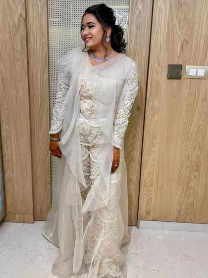 A full-length view of the bride's unique white sangeet outfit, with her hair in a chic, embellished ponytail.