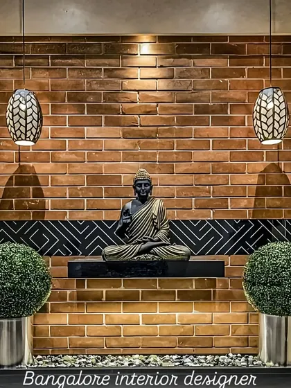 A tranquil corner featuring a Buddha statue set against an exposed brick wall. The hanging pendant lights and minimalist shelf create a peaceful and meditative focal point in the home.