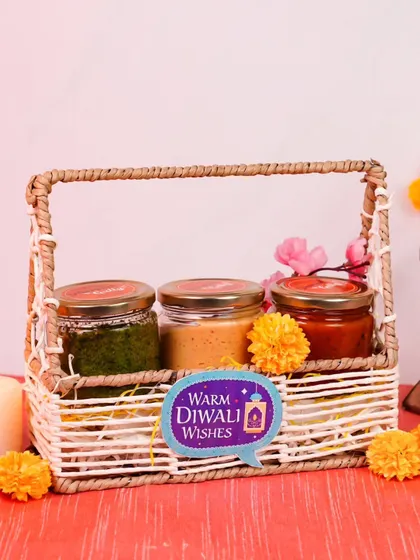 A charming and rustic Diwali gift basket. This option contains three jars of my signature dips and chutneys, perfect for someone who loves to entertain. The basket is decorated with marigold flowers and a "Warm Diwali Wishes" tag.