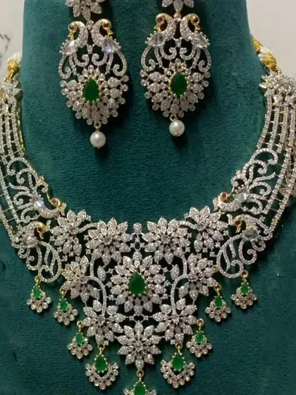 A delicate diamond-look choker with intricate floral patterns and green stone drops. This is a great option for a modern, elegant look for a reception or cocktail party.