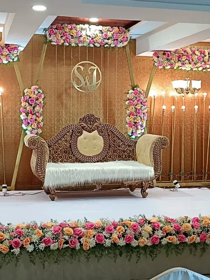 This engagement stage features a rich, textured gold backdrop with beautiful pink and peach floral arrangements. The design is both classic and modern, suitable for a variety of celebratory events.