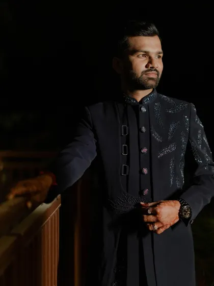 A classic, handsome portrait of the groom on the Sangeet night. The dark, moody lighting adds a touch of sophistication and drama to the shot.