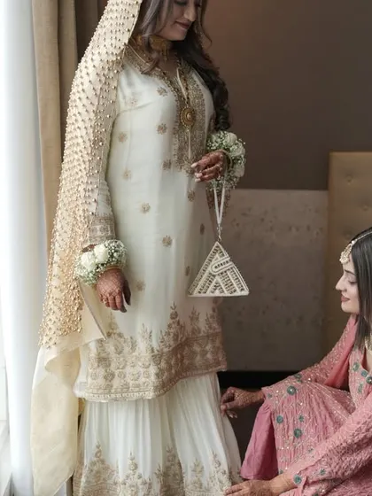 A sister adjusts the bride's dress, a candid moment of care and attention to detail.