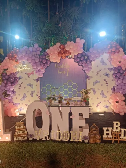 An outdoor butterfly-themed first birthday party. The marquee letters and props create a beautiful setup against the natural backdrop.