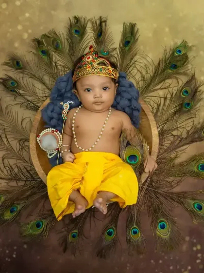 An overhead shot of the full Krishna setup, with the baby lying in a basket surrounded by a fan of peacock feathers.
