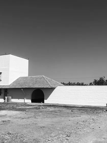 A black and white image of a project near completion, highlighting its strong, sculptural form against a clear sky.