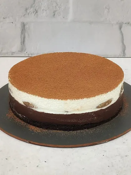 My Tiramisu Cheesecake, a perfect blend of coffee and cream. This cake has a rich chocolate and coffee base, a creamy cheesecake layer, and is dusted with cocoa powder.