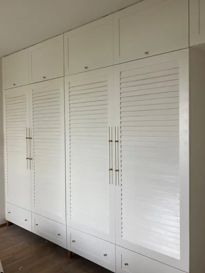When your wardrobe blends in so well, even your clutter starts behaving. A seamless, all-white wardrobe with louvered doors for a touch of texture.