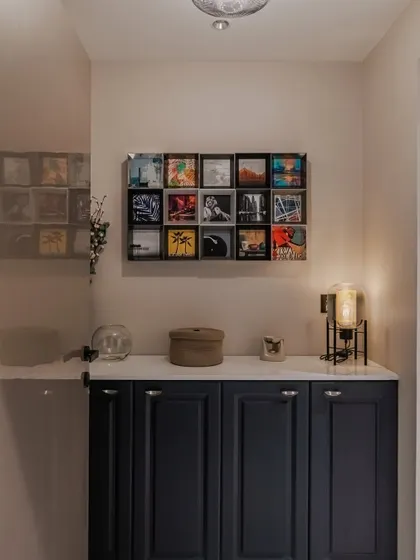 Elevate your entrance with a statement piece. This indigo blue foyer unit features elegantly routed shutters, a crisp white European membrane top, and sleek black knobs, all crowned by a captivating grid of wall art.