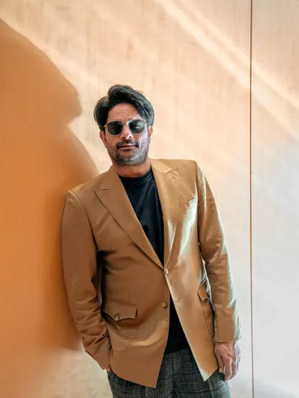 A relaxed and confident pose. The warm sunlight complements the tan blazer beautifully.